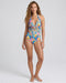 Woman wearing a colorful floral one-piece swimsuit on a white background
