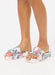 A pair of platform slide sandals with a colorful floral print on a white base, shown on a model's feet against a plain white background.