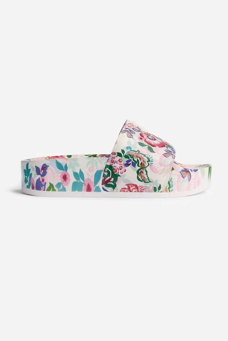 A single floral print slide sandal with a white base and a vibrant multicolor pattern of pink, green, and blue flowers, shown against a plain light gray background.