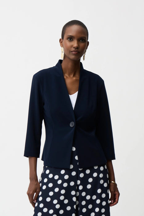 Woman wearing a midnight blue fitted silky knit jacket with shawl collar and single-button closure, styled over a polka dot pants.