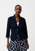 Woman wearing a midnight blue fitted silky knit jacket with shawl collar and single-button closure, styled over a polka dot pants.