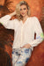 Woman wearing white button front v-neck blouse with floral embroidered raglan sleeves from Charlie B