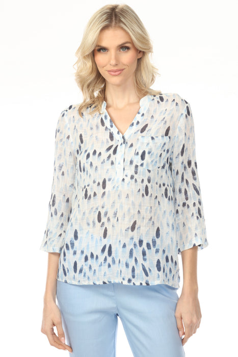Woman wearing a light blue v-neck henley blouse with a subtle pattern and roll-up sleeves from Charlie B
