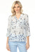 Woman wearing a light blue v-neck henley blouse with a subtle pattern and roll-up sleeves from Charlie B