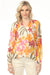Woman wearing a colorful floral v-neck blouse with long raglan sleeves from Charlie B