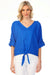 Woman wearing a blue v-neck blouse with a front tie detail and roll-up sleeves from Charlie B