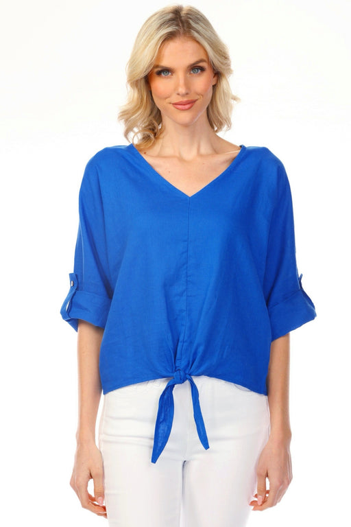 Woman wearing a blue v-neck blouse with a front tie detail and roll-up sleeves from Charlie B