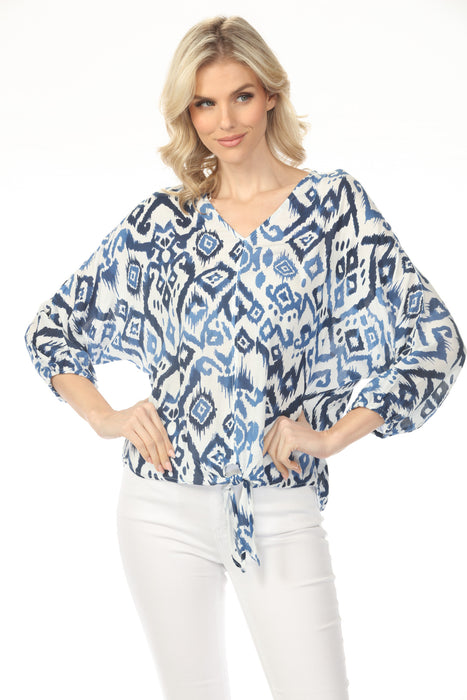 Woman wearing a blue and white ikat patterned v-neck blouse with batwing sleeves from Charlie B