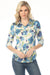 Woman wearing a floral blouse with button-up front and roll-up sleeves from Charlie B