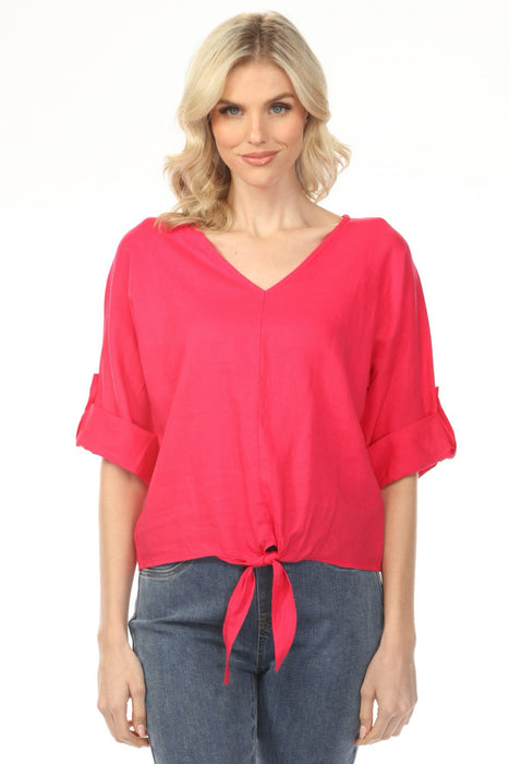 Woman wearing a bright pink v-neck blouse with a front tie detail and roll-up sleeves from Charlie B