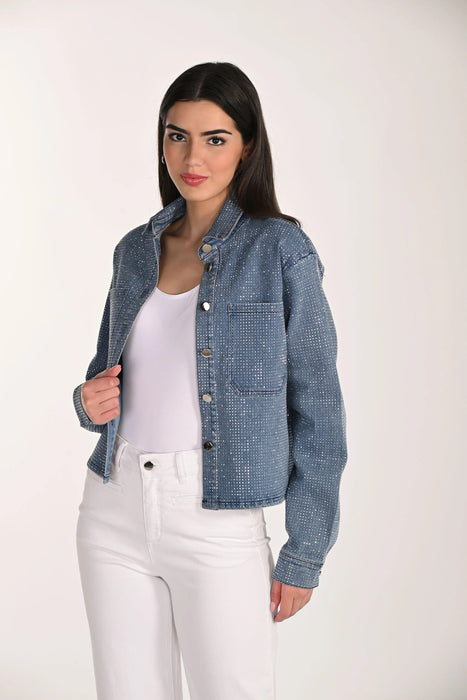 A woman modeling a cropped, long-sleeve blue denim jacket with a subtle textured pattern, worn open over a white tank top and white pants, against a plain light background.