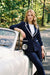 A woman wearing a navy blue tailored blazer with white piping trim from Frank Lyman