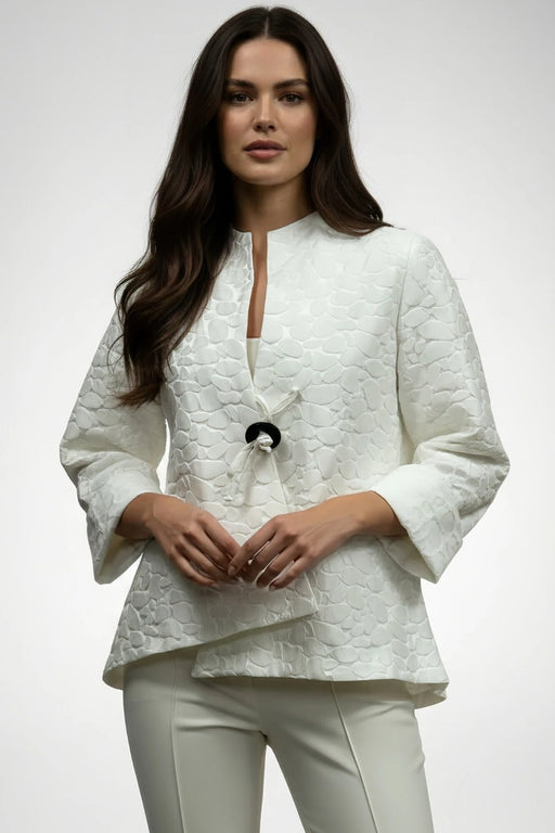 Woman wearing a white textured jacket with one button closure and asymmetric hem