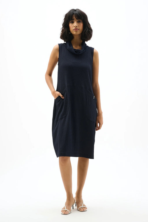 Woman wearing a sleeveless funnel collar trapeze dress with front pockets in a relaxed cocoon silhouette for a modern minimalist look