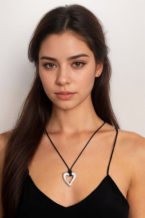 Woman wearing a black cord tie necklace with silver-tone heart pendant from Johnny Was