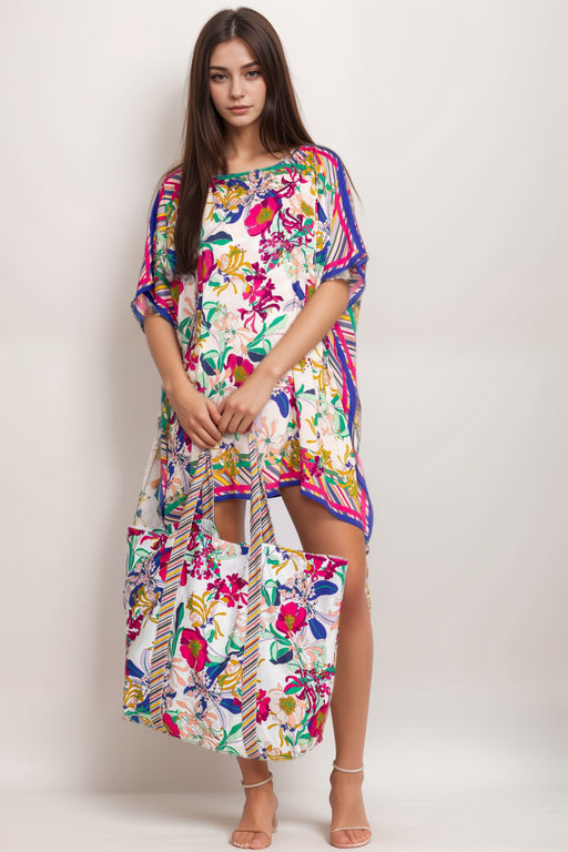 Woman carrying a colorful floral beach tote bag with striped handles from Johnny Was