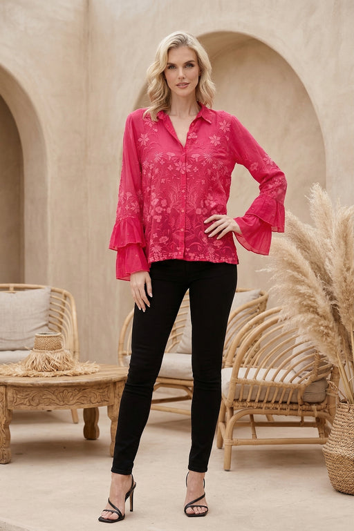 Woman wearing a pink blouse with floral embroideries ruffled long sleeves from Johnny Was
