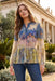 Woman wearing a colorful blouse with floral patterns in an outdoor setting.