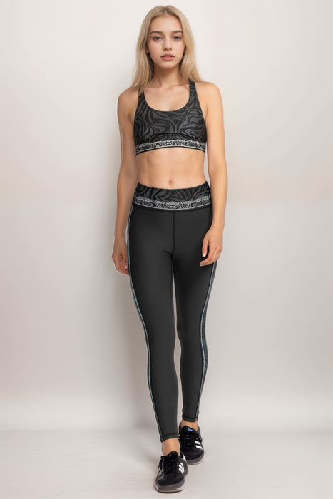 Woman wearing a black activewear legging with animal print waistband and side panels from Johnny Was