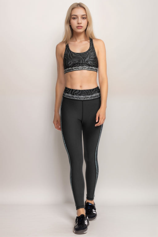 Woman wearing a black activewear legging with animal print waistband and side panels from Johnny Was