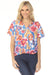 Woman wearing a colorful floral t-shirt with collared v-neck and short sleeves from Johnny Was