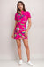 Woman wearing a bright pink tennis dress with colorful floral pattern from Johnny Was