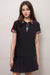 Woman wearing a black activewear polo tee with colorful floral trim and short sleeves from Johnny Was