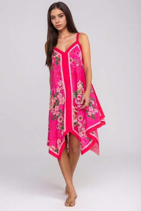 Woman wearing a bright pink dress with floral pattern and handkerchief hem from Johnny Was