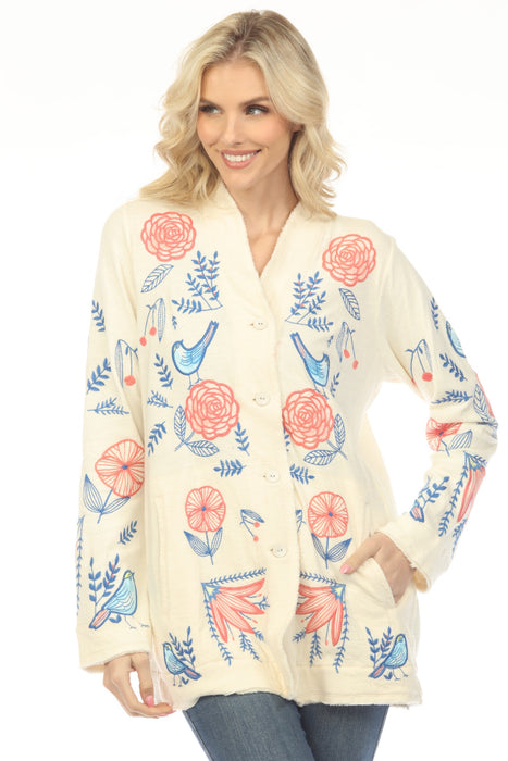 Woman wearing a cream-colored cardigan with floral and bird embroideries and side pockets from Johnny Was