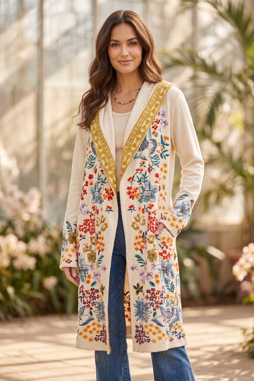 Woman wearing a beige open front duster cardigan with colorful floral embroideries and hood from Johnny Was