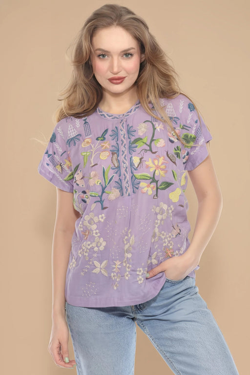 Woman wearing a purple embroidered blouse with floral patterns, henley and short sleeves from Johnny Was