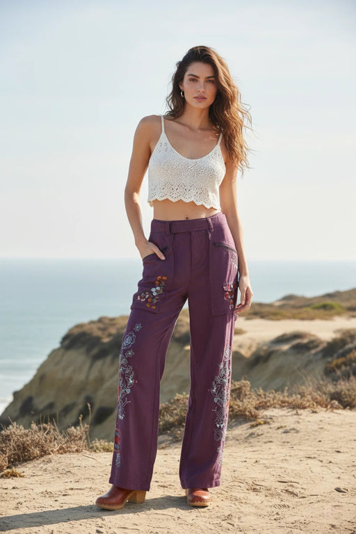Woman wearing plum-colored embroidered wide leg pants with belt and pockets from Johnny Was