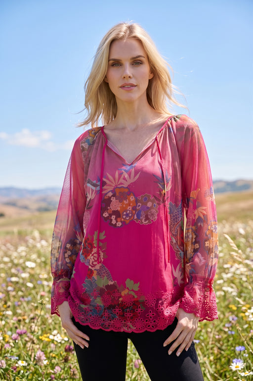 Woman wearing a pink printed mesh top with lace trim and split v-neck with tie from Johnny Was