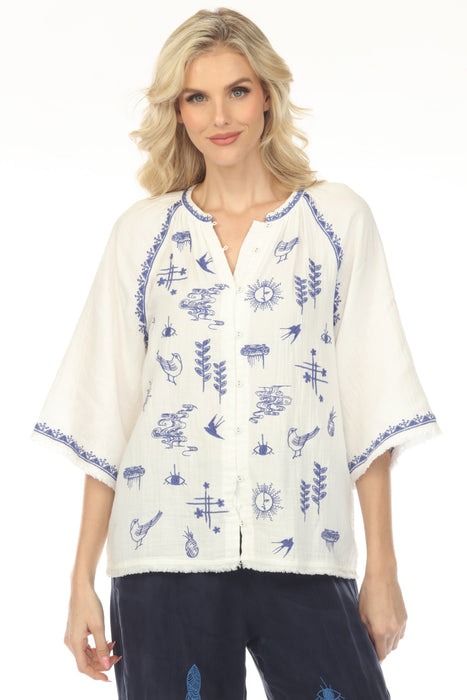 Woman wearing a white top with blue embroideries and button front closure from Johnny Was