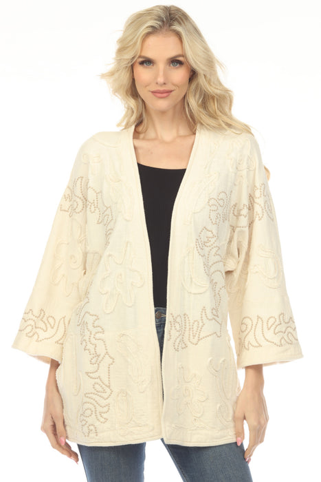 Woman wearing a cream-colored embroidered kimono-style jacket with open front and side pockets from Johnny Was