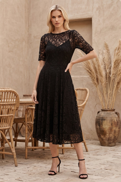 Woman wearing a black midi lace dress with short sleeves and flowy skirt from Johnny Was