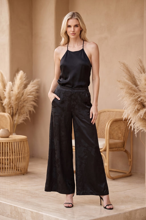 Woman wearing black flared pants with tone on tone floral pattern and pockets from Johnny Was