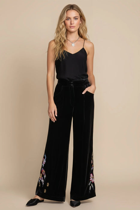 Woman wearing a black embroidered wide leg velvet pants from Johnny Was
