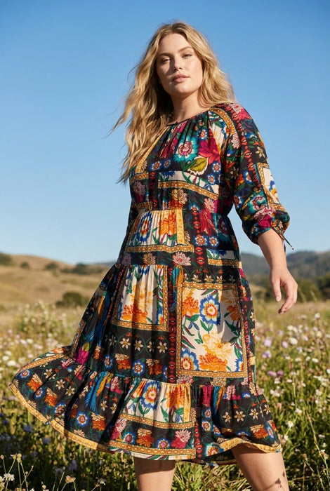 Woman wearing a colorful floral patchwork patterned midi dress from Johnny Was