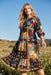 Woman wearing a colorful floral patchwork patterned midi dress from Johnny Was