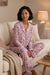 Woman wearing a matching floral printed button down top and pajama pants from Johnny Was