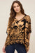 Woman wearing a gold and black patterned top with v-neck and elbow sleeves from Johnny Was