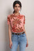 Woman wearing a pink tropical palm tree print mesh top with short sleeves from Johnny Was
