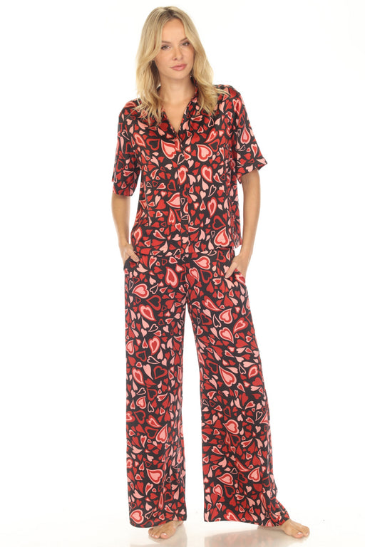 Woman wearing a red and black heart patterned silk pajama set from Johnny Was