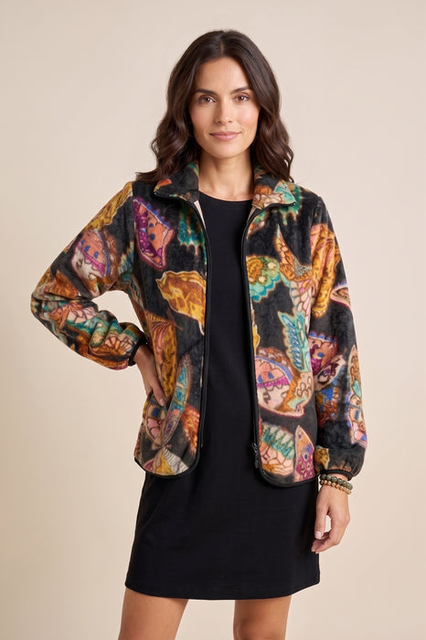 A woman modeling a lightweight zip-up jacket with a vibrant multicolor butterfly print over a black dress, set against a solid beige background.