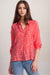 Woman wearing a coral breathable shirt with tonal embroidery and button down closure