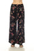 Woman wearing a black velour wide leg pant with floral and butterfly pattern from Johnny Was