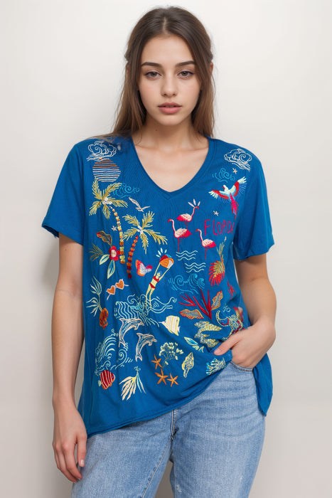Woman wearing a blue t-shirt with colorful embroideries and v-neck from Johnny Was