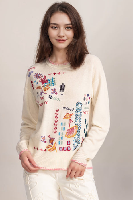 Woman wearing a wool cashmere blend cream sweater with front embroideries and long sleeves
