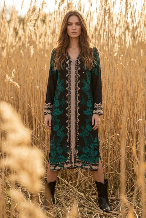 Woman wearing a black and teal floral silk midi dress with v-neck and long sleeves from Johnny Was